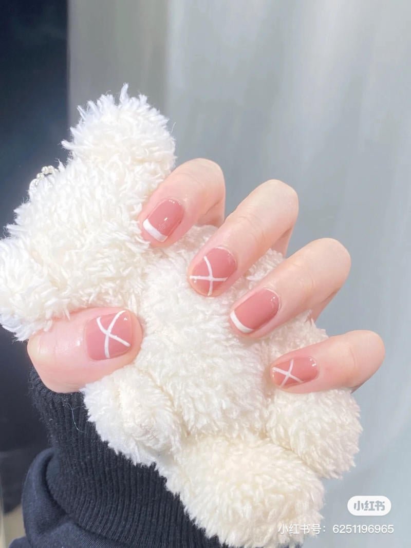 mau-nail-don-gian-cardina__106__fd85e9ccbec04856950b73a0327846f4 Bàn tay đeo găng len đen, móng tay sơn màu hồng nhạt viền trắng, cầm thú bông trắng.