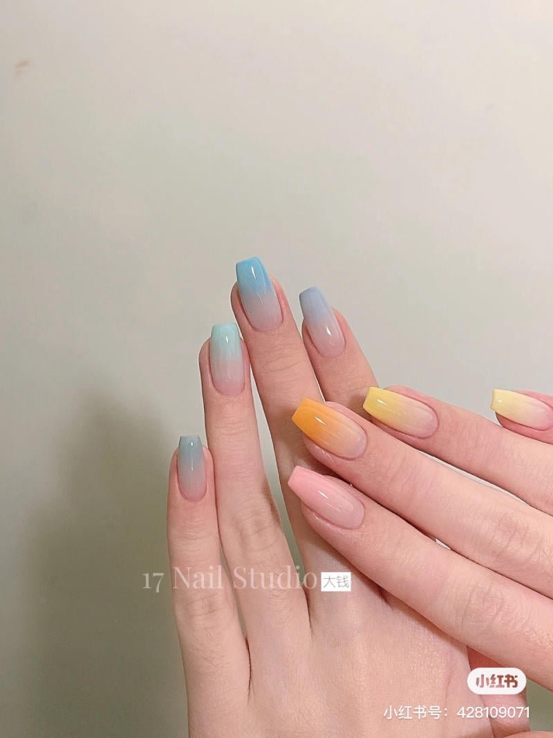 mau-nail-don-gian-cardina__121__59120399c5994102b3b65d7080420a8d Bàn tay với móng tay được sơn ombre màu xanh và vàng, nền màu trắng.